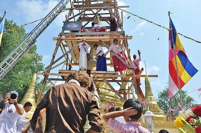 Candy and popcorn flies as the final piece of the crown is put in place at the top of the pagoda in Akron on Sunday, Aug. 26, 2018.